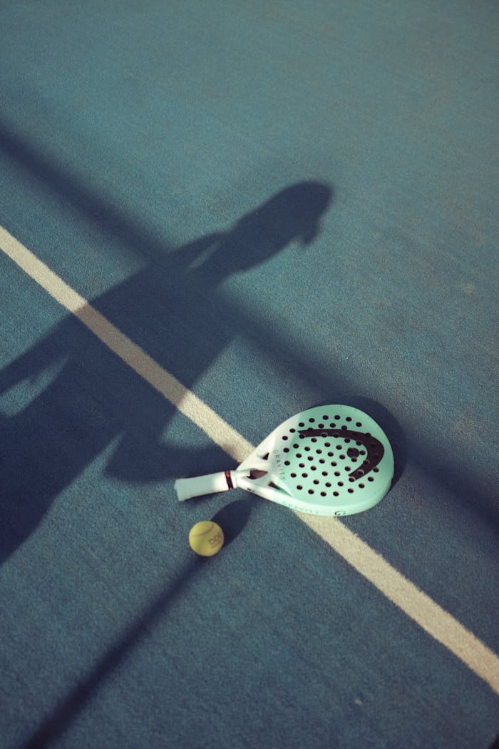 Artistic shadow of player with padel racket on court surface.